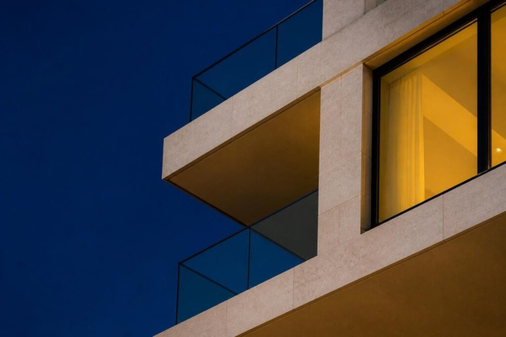 Moderner Balkon mit beleuchtetem Fenster in der blauen Stunde