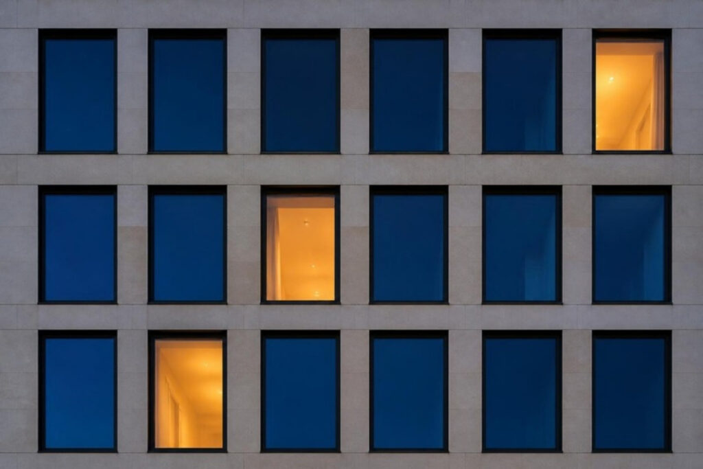 Fassade mit einzelnen beleuchteten Fenstern am Abend