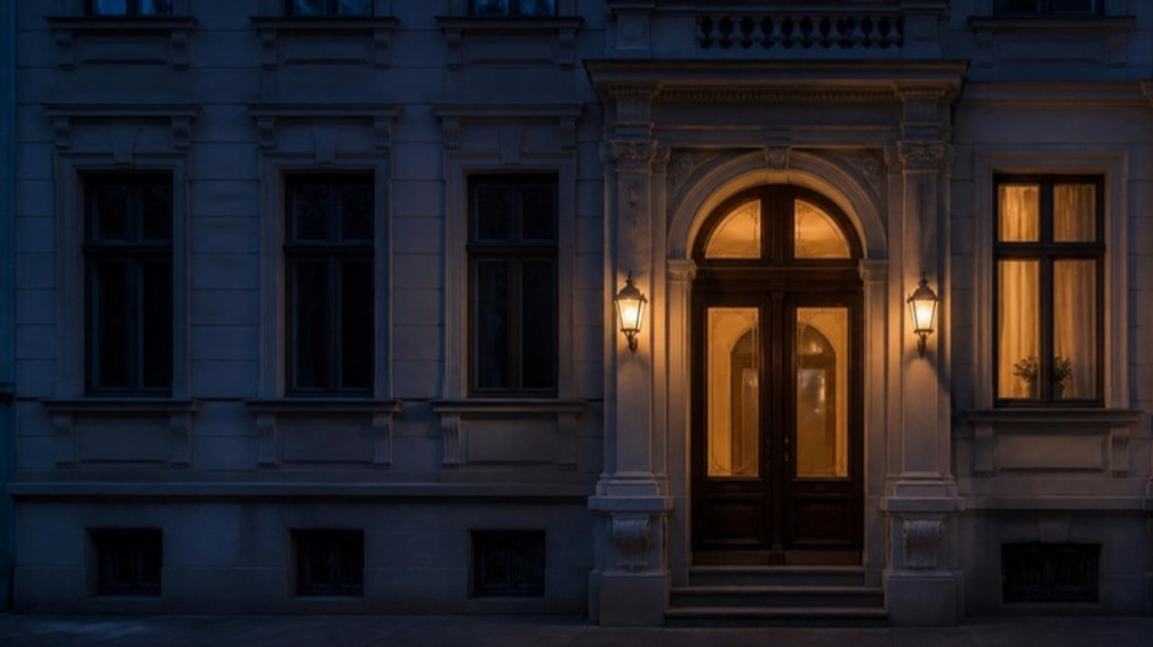 Altbau-Eingangsportal mit Laternen am Abend